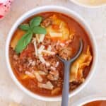 A bowl of ravioli soup with a spoon.