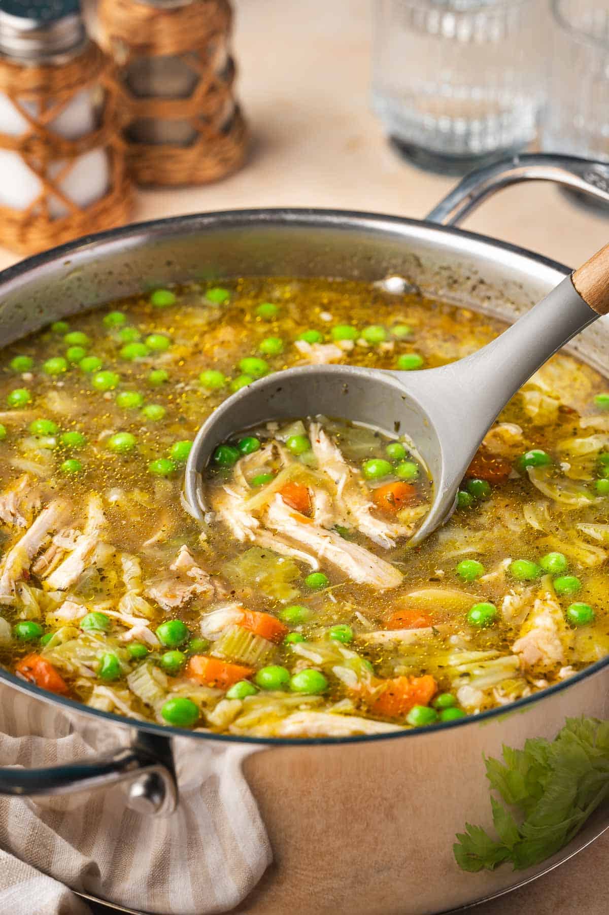 A pot of chicken and cabbage soup with a silicone ladle scooping some soup out.