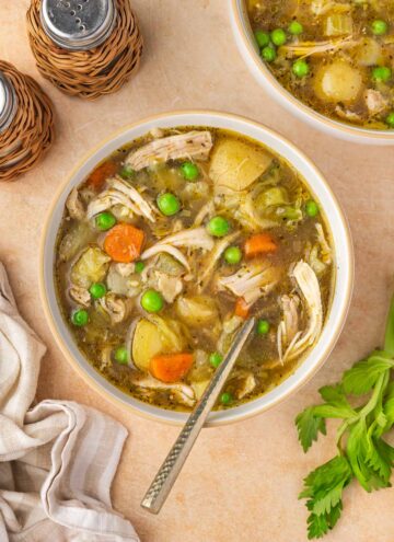 A bowl of chicken and cabbage soup with a spoon.