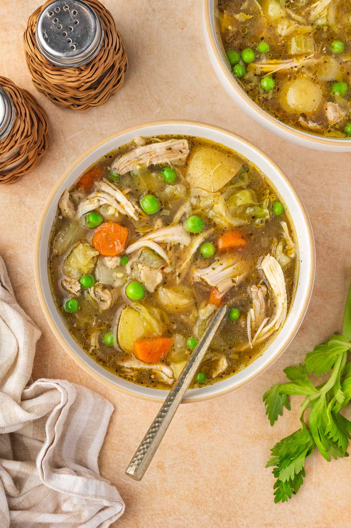 A bowl of chicken and cabbage soup with a spoon.