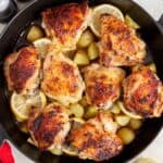 Overhead view of cast iron chicken thighs and potatoes.