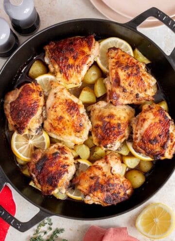 Overhead view of cast iron chicken thighs and potatoes.