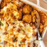 Overhead view of a baking dish of dump and bake meatball casserole with a portion scooped out and the serving spoon tucked under two meatballs.