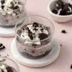 An angled view of a jar of no-bake Oreo cheesecake cup with more off to the side.