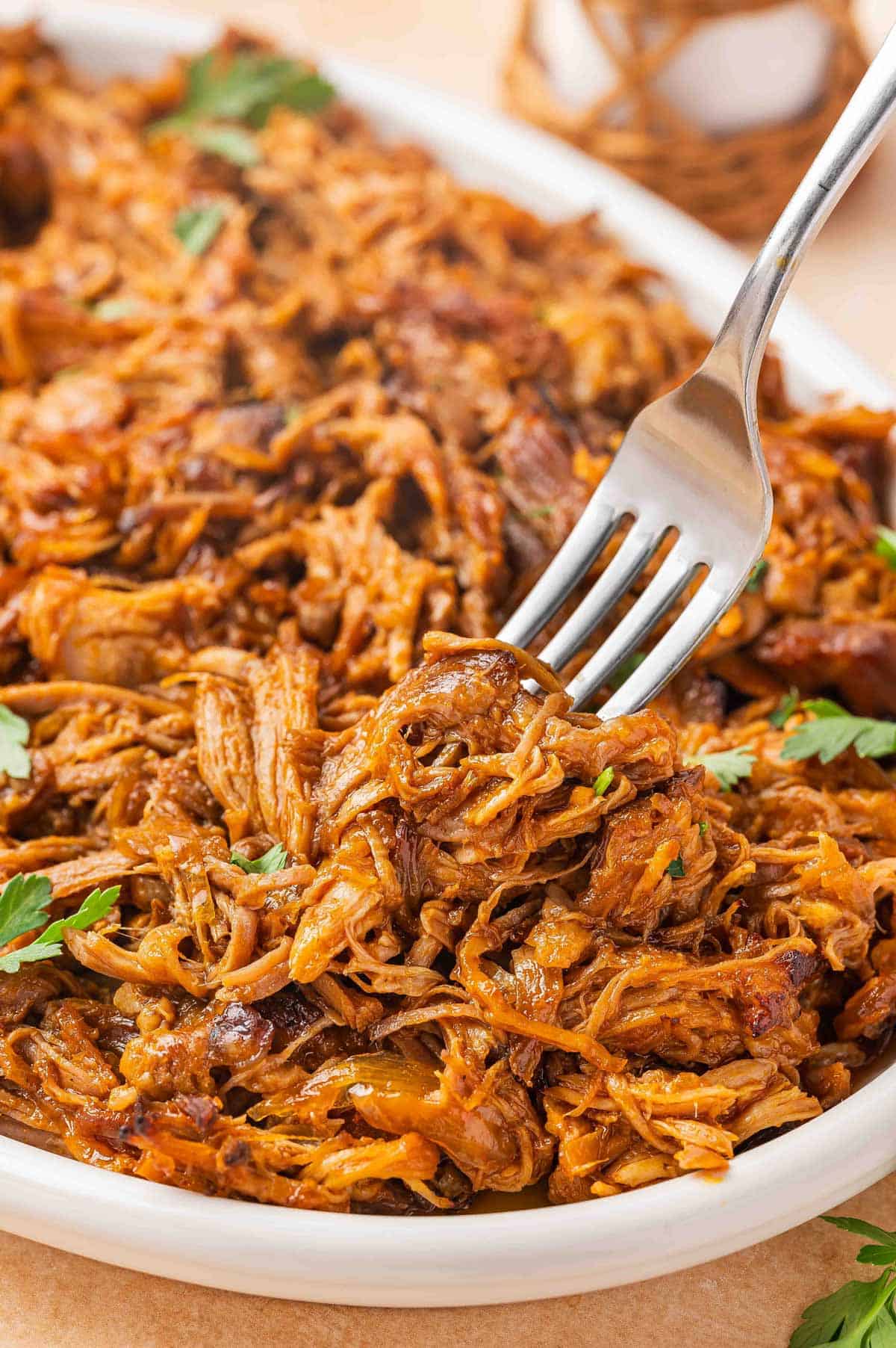 A fork lifting up a bit of slow cooker gochujang pulled pork from a platter.