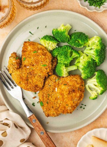 A plate with two air fryer panko chicken thighs and broccoli with a fork.